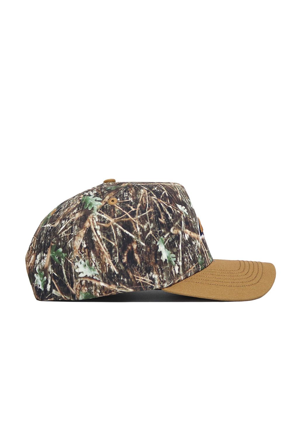 The Montana State Camo Hat - Explorer Edition has a brown brim and a camo crown with green leaves and brown branches, shown from the side on a white background. Its structured fit offers lasting style and comfort.