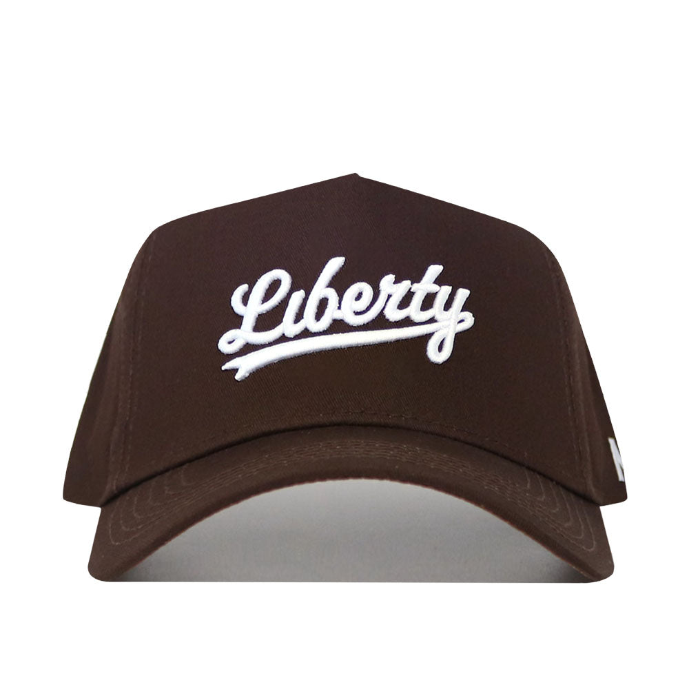The Liberty Americano Hat is a structured fit brown baseball cap made from high quality cotton, featuring "Liberty" embroidered in white cursive on the front.