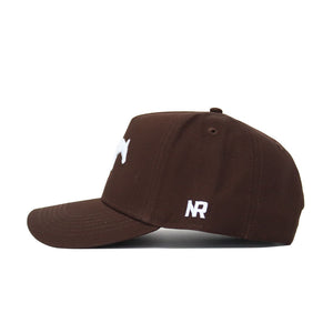 The SMU Americano Hat is a brown snapback made of high-quality cotton, with a white NR embroidered on the side and a partially visible white front logo, shown in a side profile view.