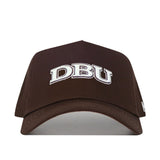 The DBU Americano Hat is a brown, structured baseball cap featuring white embroidered DBU letters on the front, shown from the front against a white background.