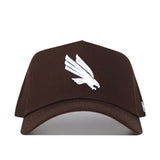 The North Texas Americano Hat is a brown cotton baseball cap featuring a white embroidered bird logo, structured fit, curved brim, and detailed stitching for a premium appearance.