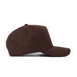 The North Texas Americano Hat is a brown snapback shown on its side, highlighting the left profile, curved brim, and six-panel structured fit made from high-quality cotton.
