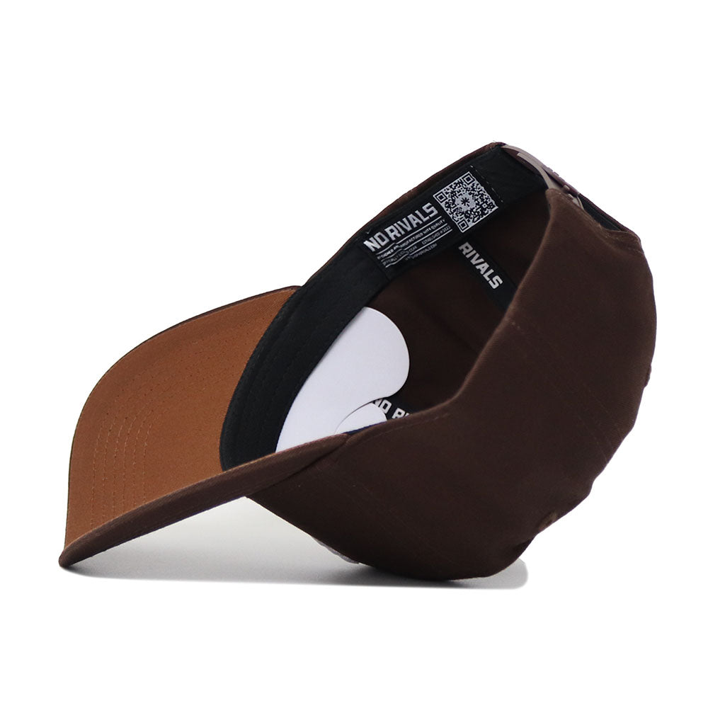 The North Texas Americano Hat, a brown snapback, is shown upside down with its tan brim, black inner band featuring white "NO RIVALS" text, a small white tag, a QR code inside, and its structured fit on display.