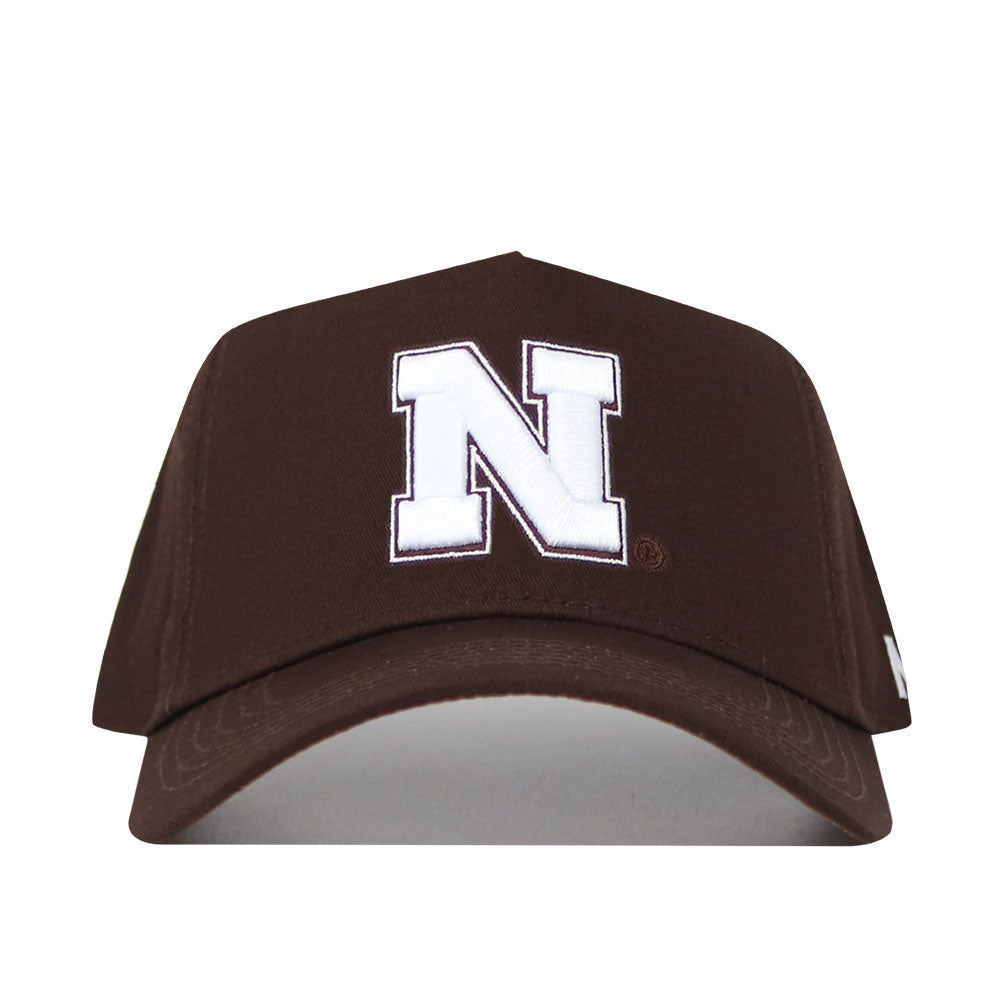 The Nebraska Americano Hat is a structured brown baseball cap featuring a bold white 'N' on the front and a comfortable snapback closure for an adjustable fit.