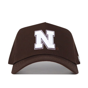 The Nebraska Americano Hat is a structured brown baseball cap featuring a bold white 'N' on the front and a comfortable snapback closure for an adjustable fit.
