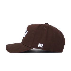 A brown Oklahoma State Americano Hat viewed from the side, made of soft cotton, featuring white embroidered "NR" near the back and a partial white logo on the front.