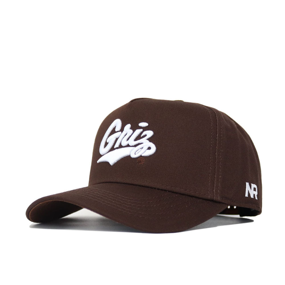 The University of Montana Americano Hat by No Rivals is a brown baseball cap made from high-quality cotton, featuring "Griz" embroidered in white on the front, "NR" on the side, a curved brim, structured fit, and adjustable back strap.