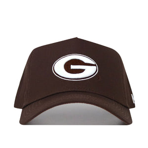 The Georgia Americano Hat is a brown snapback made from high-quality cotton, featuring a white oval emblem with a bold brown "G" outlined in black on the front for a comfortable, structured fit.
