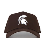 The Michigan State Americano Hat is a brown, structured baseball cap made from high-quality cotton, featuring a white Spartan helmet logo on the front.