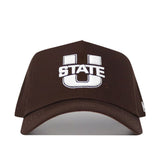 The Utah State Americano Hat is a brown snapback featuring a large white embroidered "U" with "STATE" stitched across the center in white.
