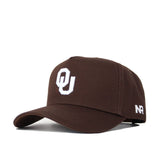 The Oklahoma Americano Hat is a dark brown snapback with a white OU logo on the front and white NR lettering on the side. Made from high quality cotton, it has a curved brim, structured fit, and an adjustable back strap.