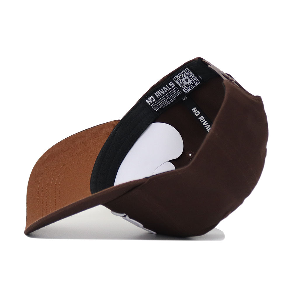 The Mississippi State Americano Hat, a brown snapback, is flipped upside down to display its black interior band and inner label repeatedly printed with "NO RIVALS." The cap rests on a white surface.