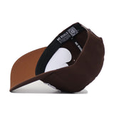 The Mississippi State Americano Hat, a brown snapback, is flipped upside down to display its black interior band and inner label repeatedly printed with "NO RIVALS." The cap rests on a white surface.