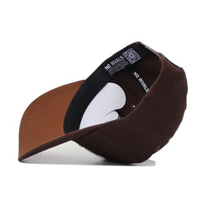 The Nevada Americano Hat, a brown snapback crafted from high-quality cotton, is shown upside down on a white surface. Its inner band features “NO RIVALS” text and a QR code, highlighting the structured fit and attention to detail.