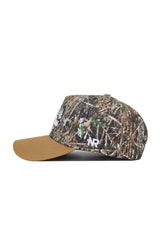 The Scheels Camo Explorer Hat features a brown suede bill, green-brown-tan camo crown, and white "NR" embroidery on the side. Enjoy a structured fit for style and durability.