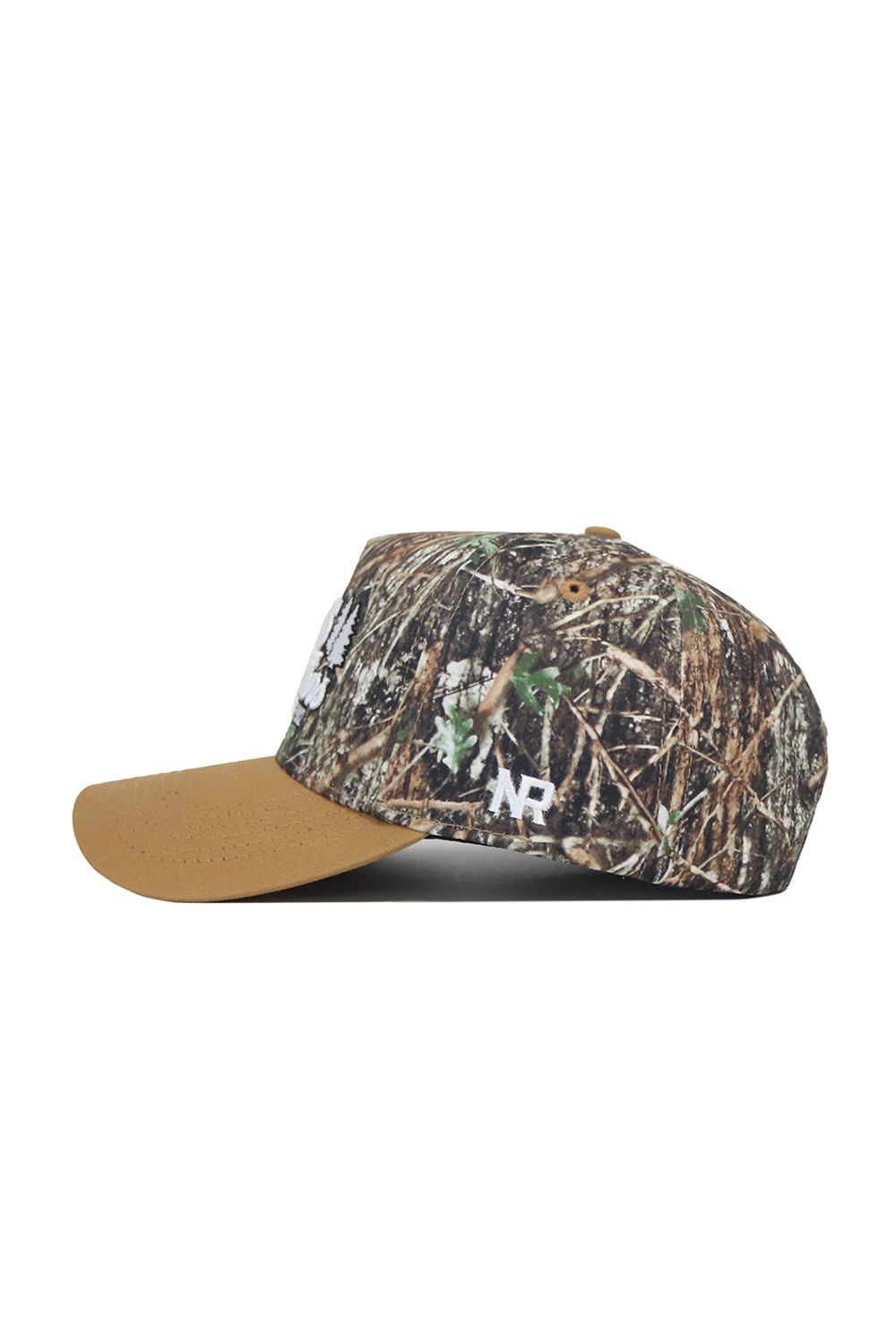 The Scheels Camo Explorer Hat features a brown suede bill, green-brown-tan camo crown, and white "NR" embroidery on the side. Enjoy a structured fit for style and durability.