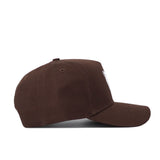 The Houston Americano Hat is a brown snapback baseball cap with a curved brim and top button, shown from the side. This structured-fit hat has a clean, minimal look and is displayed on a white background.