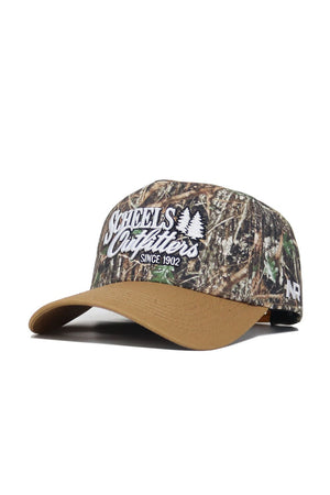 The Scheels Camo Explorer Hat is a structured fit camo baseball cap made from quality cotton, featuring a tan brim, white "Scheels Outfitters Since 1902" embroidery with tree graphics, an "NR" side logo, and an adjustable snapback closure.