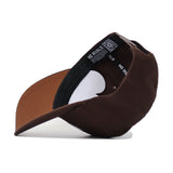 The Mizzou Americano Hat is a brown snapback featuring a black inner lining with “NO RIVALS” in white. It has a structured fit, slightly curved brim, adjustable strap, and showcases high-quality cotton construction.