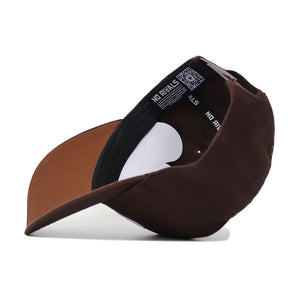 The Mizzou Americano Hat is a brown snapback featuring a black inner lining with “NO RIVALS” in white. It has a structured fit, slightly curved brim, adjustable strap, and showcases high-quality cotton construction.