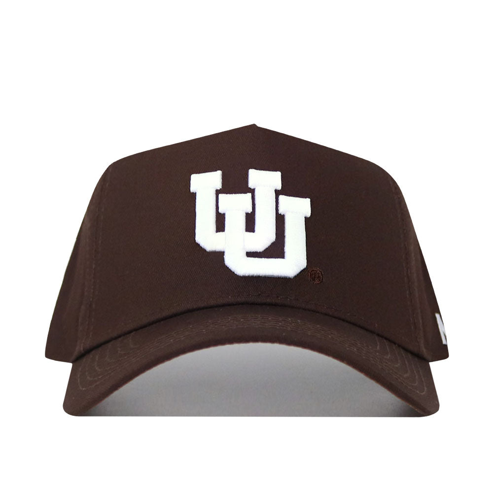 The Utah Americano Hat is a brown snapback made from high-quality cotton, featuring a white embroidered interlocking UU logo on the front.