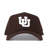 The Utah Americano Hat is a brown snapback made from high-quality cotton, featuring a white embroidered interlocking UU logo on the front.