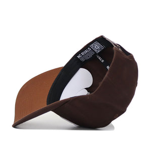 The Utah Americano Hat is a brown snapback shown upside down, revealing a black sweatband, a NO RIVALS tag, and a white cardboard insert inside its curved-brim, structured crown.