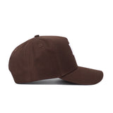 The Baylor Americano Hat is a brown baseball cap seen from the side, featuring a curved brim and top button. Made from high quality cotton, it has a plain design with no visible logos or decorations on the side.