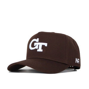 The Georgia Tech Americano Hat is a brown cotton baseball cap featuring "GT" embroidered in white on the front and "NR" stitched on the side. It offers a structured fit, curved brim, and adjustable back strap.