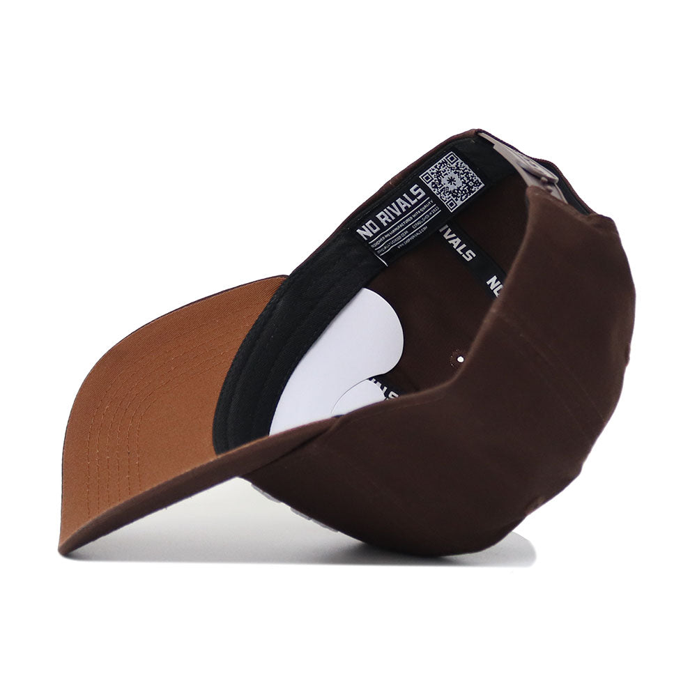 The Wake Forest Americano Hat is a brown snapback shown upside down, displaying its black and white lined interior with visible NO RIVALS branding on the inner band. Crafted from high-quality cotton for a comfortable, structured fit.