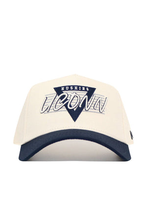 The UConn Triangle Game Cap Hat is a structured white cotton baseball cap with a navy brim, featuring a triangular "HUSKIES" patch above large embroidered "UCONN" text on the front.
