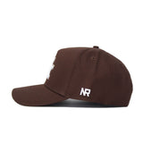 The Kentucky Americano Hat, a brown baseball cap made of high-quality cotton with white embroidered NR letters on the side, is shown in profile against a white background.