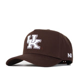 The Kentucky Americano Hat is a brown snapback featuring a bold white UK logo on the front and NR initials on the side. Made from high-quality cotton for a structured fit, it's shown angled against a white background.