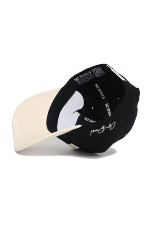 A black and white WAKE FOREST Established Hat by No Rivals is shown upside down, revealing inside labels. Made from high-quality cotton, it features a white signature on the black section of the cap.