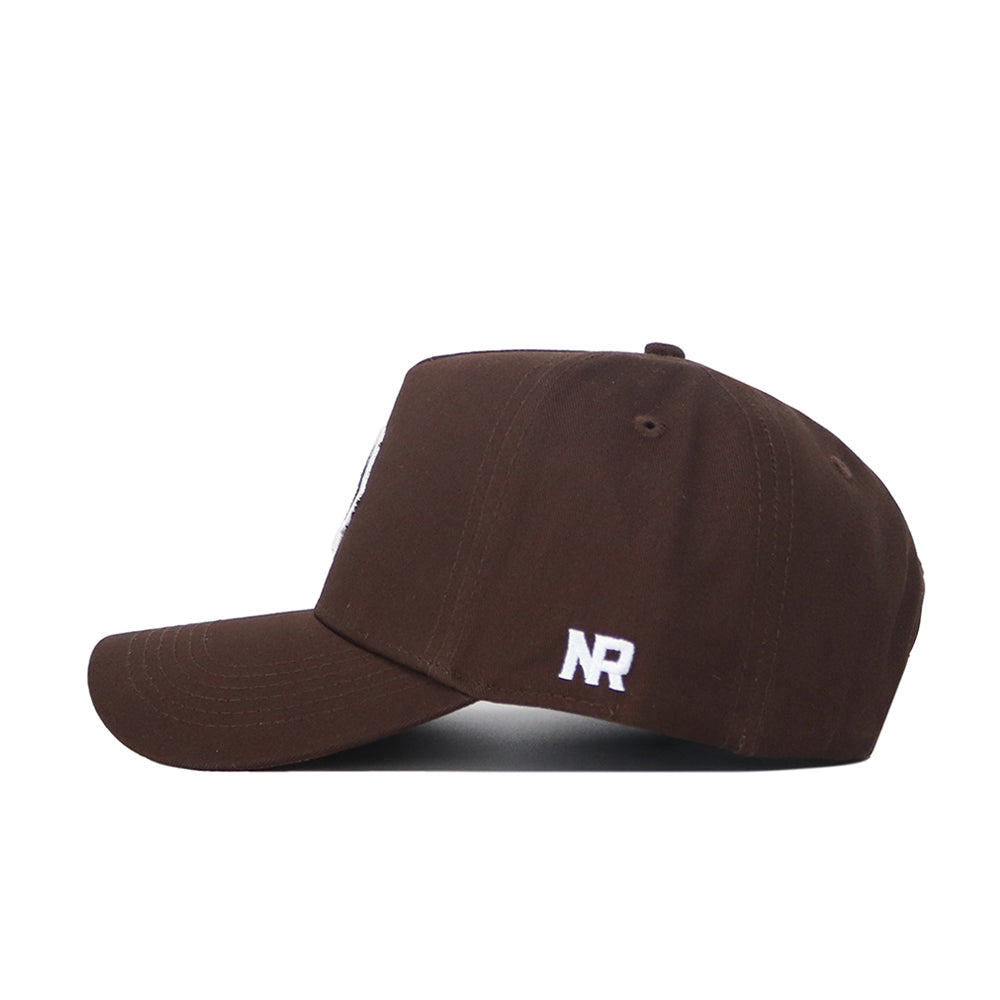 The UConn Americano Hat is a brown snapback with a structured fit, crafted from high-quality cotton. White embroidered NR lettering accents the left side near the back, as seen from a side view.