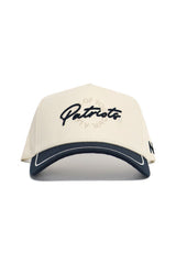 The No Rivals DBU Patriots ALOYO Hat is a cream snapback with "Patriots" in black script, a black visor with white trim, quality cotton structured fit, and a small black side detail.
