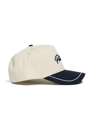 The No Rivals DBU Patriots ALOYO Hat is a beige baseball cap with a curved black brim, white trim, and black embroidered front text, made from high quality cotton in a structured fit, shown side view on a white background.