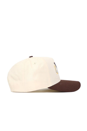 The Wyoming Triangle Game Cap Hat is a beige baseball cap with a brown brim, shown from the side on a white background. This structured snapback features embroidery visible on the front panel’s edge.