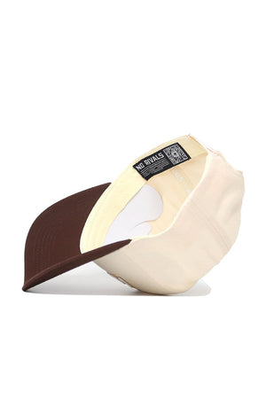 The Wyoming Triangle Game Cap Hat is a beige and brown snapback shown upside down, revealing its cream interior, sweatband, and black "NO RIVALS" tag with QR code. This structured cap is made from high-quality cotton for lasting comfort.