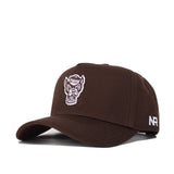 The NC State Americano Hat is a brown snapback made from high-quality cotton, featuring an embroidered wolf head logo on the front and white "NR" letters on the side.