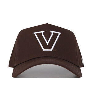 The Vanderbilt Americano Hat is a structured brown snapback cap made from premium cotton, featuring a large white embroidered "V" on the front and a curved brim. It is shown against a plain white background.