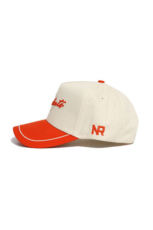 The SHSU Bearkats ALOYO Hat by No Rivals is a cream structured snapback with a red brim and accents, made from premium cotton. It features red NR initials on the side and red cursive embroidery on the front.