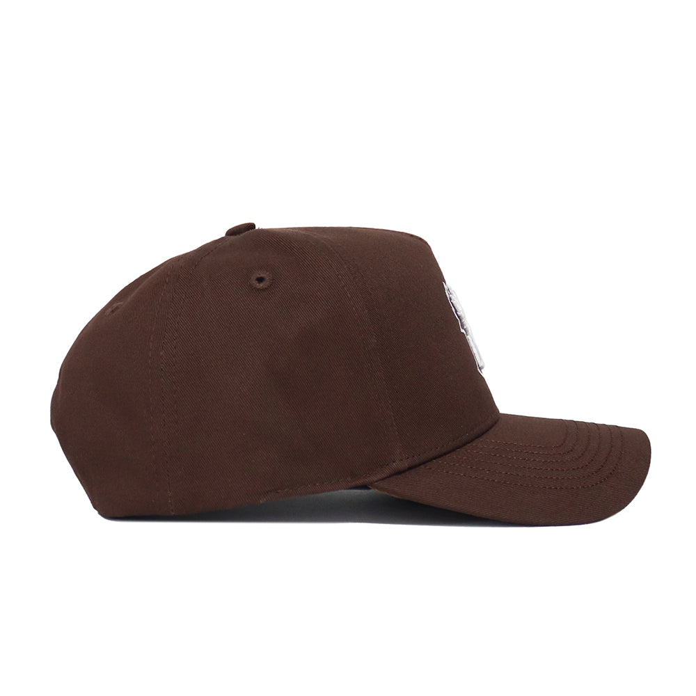 The Creighton Americano Hat, shown in profile from the left, is a brown baseball cap crafted from high-quality cotton with a curved brim, structured fit, and an unadorned surface.