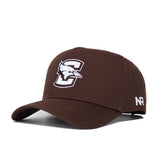 The Creighton Americano Hat is a brown snapback made from high-quality cotton, featuring a large embroidered C with a stylized bird head on the front and white NR letters stitched on the left side.