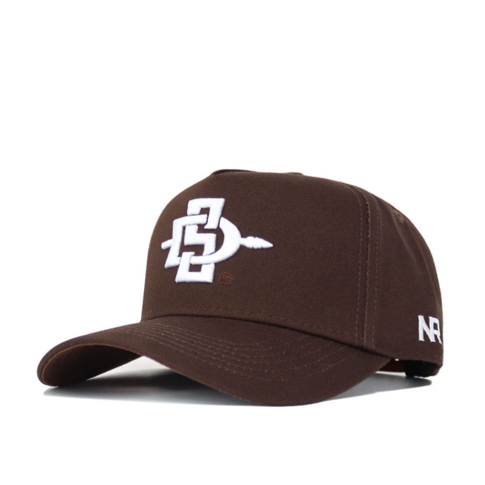 The San Diego State Americano Hat is a brown baseball cap with a white embroidered logo of intertwined letters and a spear on the front, white side text, structured fit, and snap back closure.