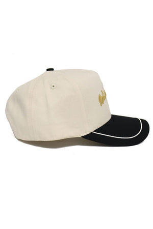 The No Rivals Wake Forest ALOYO Hat is a beige cotton baseball cap with a black curved brim and white trim, gold side embroidery, metal eyelets for ventilation, and an adjustable snap back for a perfect fit.