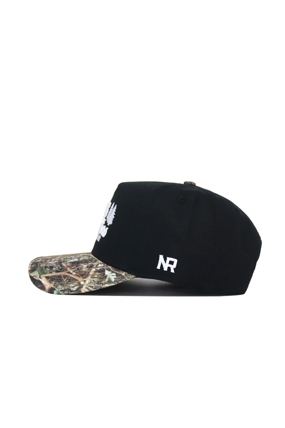The Scheels Camo Trailblazer Hat is a black snapback with a camo brim, white embroidered front and side logos, made from high-quality cotton for a structured fit. Shown in side profile.
