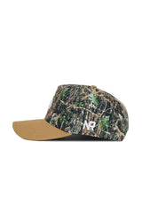 The Texas State Camo Hat - Explorer Edition by No Rivals is a structured snapback cap with a brown visor, a camouflage crown featuring green leaves and branches, and white NR initials embroidered on the side.