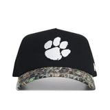 The No Rivals Clemson Camo Hat - Trailblazer Edition is a structured black cap with a white paw print logo and a camouflage-patterned brim, crafted from high quality cotton.