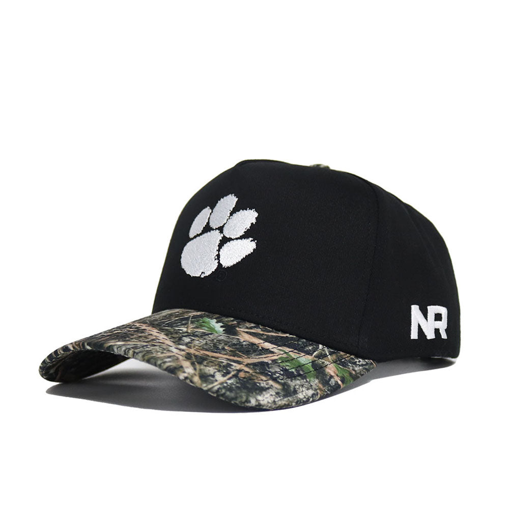 The No Rivals Clemson Camo Hat - Trailblazer Edition is a high-quality cotton black cap with a white paw print logo, camouflage visor, structured fit, and "NR" embroidered in white on the side.